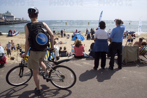 ENGLAND, Dorset, Bournemouth, Tourists playing in the sand and watching speedboat races off the West Beach beside the pier