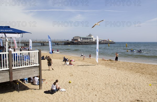ENGLAND, Dorset, Bournemouth, Tourists playing in the sand and watching speedboat races off the West Beach beside the pier