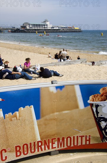 ENGLAND, Dorset, Bournemouth, Tourists playing in the sand and watching speedboat races off the West Beach beside the pier.