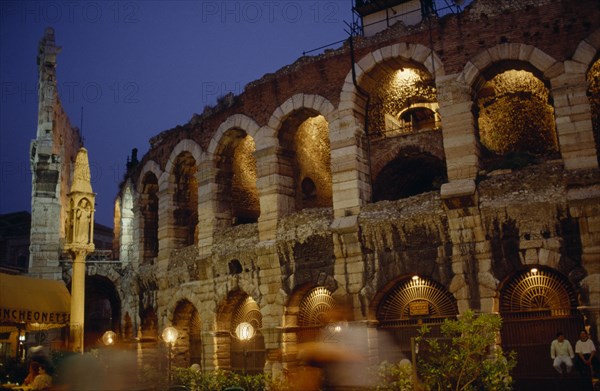 ITALY, Veneto, Verona, Teatro Romano.  Exterior facade of ruined theatre built in the 1st century BC illuminated at night with passers by in blur of movement in foreground.