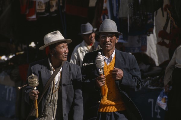 CHINA, Tibet, Lhasa, Pilgrims with prayer wheels walking through the Barkhor Bazaar