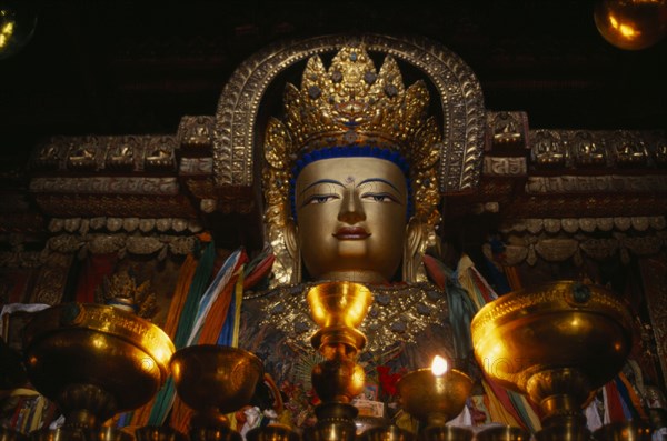CHINA, Tibet, Gyantse, "Butter lamps and a statue of Sakyamuni, the present Buddha, in Pelkor Chode Monastery."