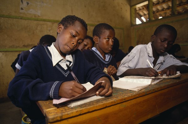 KENYA, Nairobi, Schoolchildren working at desks in classroom.