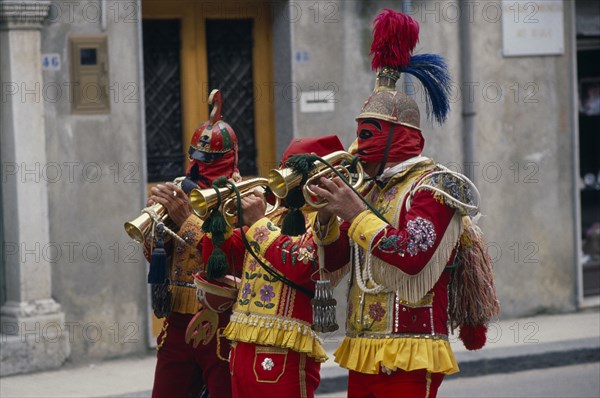 ITALY, Sicily, San Fratello, Bugle players wearing red and yellow costumes and masks celebrating the Feast of the Jews just before Easter.