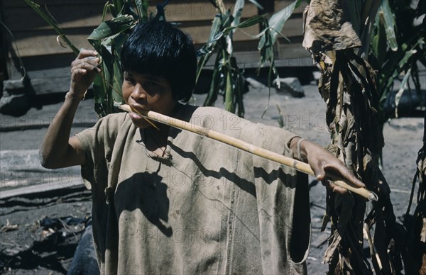 COLOMBIA, Sierra de Perija, Yuko - Motilon , Woman playing a musical bow.  The Yuko-Motilon are very musical with a wide range of musical instruments and syncopated war chants.