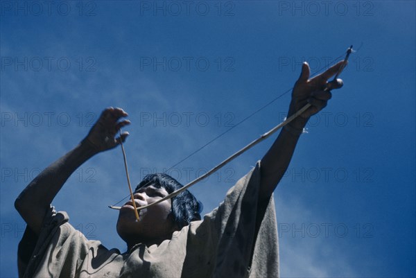 COLOMBIA, Sierra de Perija, Yuko - Motilon , Portrait of woman playing musical bow.  The Yuko-Motilon are very musical with a wide range of musical instruments and syncopated war chants.