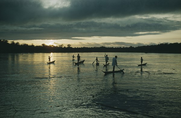 COLOMBIA, Choco Region, Noanama Tribe, Boys paddling canoes on lower rio San Juan at dusk