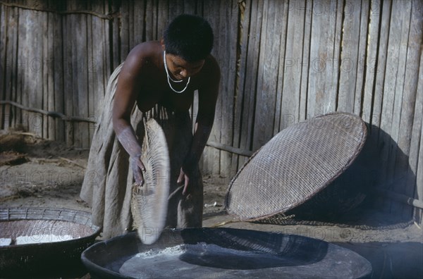 COLOMBIA, Vaupes Region, Tukano Tribe, Girl prepares clay oven for baking “casabe” yucca flour into Tukano daily bread