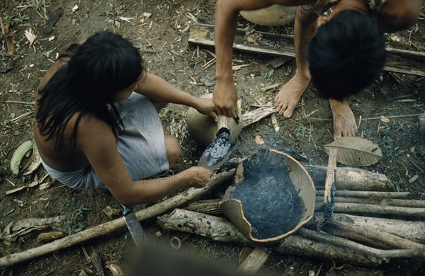 COLOMBIA, Choco Region, Noanama Tribe, Woman pouring “breo” / melted beeswax into a fired “cantaro” / clay water pot which will now be watertight
