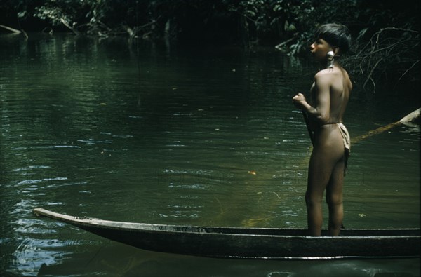 COLOMBIA, Choco Region, Noanama Tribe, "Ricardino, a young boy with a silver ear plug paddles his canoe upstream towards the family cultivation plot "