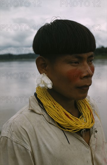 COLOMBIA, Choco Region, Noanama Tribe, "Teenager decked out with traded, yellow, glass bead necklace plus two silver crosses, denoting missionary influence, a lily in his ear for adornment"