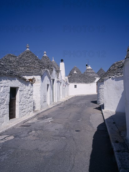 ITALY, Puglia, Bari, "White Trulli buildings with grey stone roofs in Alberobello village that have been converted into houses. No mortar is used, although the interior is plastered."