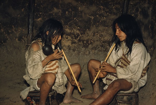 COLOMBIA, Sierra Nevada de Santa Marta, Kogi Tribe, Men playing “kuisi” flutes in San Miguel village. “macho” male flute has one hole and player waves a maraca; “embra” female flute which has five holes and maintains the melody.