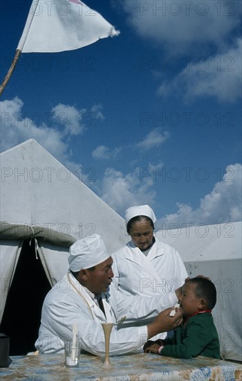 KAZAKHSTAN, Kirgiziya, Mountain doctor and nurse treating young boy.