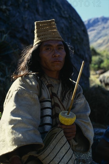 COLOMBIA, Sierra Nevada de Santa Marta, Valley of Surlivaka, Kogi mama/priest Juan Vacuna wearing distinctive woven fique/cactus fibre hat at religious centre of Surlivaka  Holds lime encrusted poporo/gourd full of fine lime powder from burnt seashells collected along Caribbean coast. The palito/stick represents male penis the gourd female vagina Continuous rubbing - signifying copulation - over years produces large lime encrustation. Lime powder on end of stick stuck into wad of coca leaves in the cheek acts as catalyst to release the cocaine alkaloid from the coca leaves. Process has intense religious and sexual significance for mamas and all traditional Kogi men