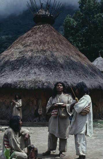 COLOMBIA, Sierra Nevada de Santa Marta, Sierra Chendukua , Chendukua traditional village Kogi mamas/priests stand outside ceremonial nuhue/ temple with grass-thatched roof and rack at apex filled with sacred potsherds   southern side of Sierra Chendukua Indigenous Tribes  Kogi