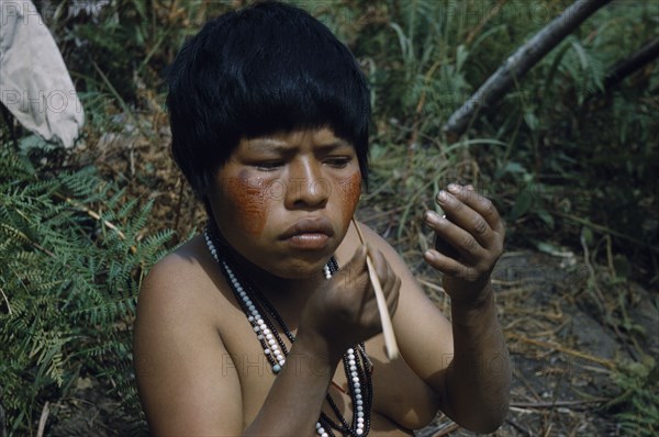 COLOMBIA, Sierra de Perija, Yuko - Motilon , Girl applying bright red “Achiote” facial paint extracted from ground Achiote seeds.