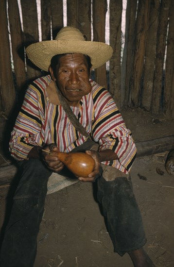 COLOMBIA, Sierra de Perija, Yuko - Motilon , "Marty, an old man, wearing a local peasant straw hat and Indian woven striped “manta”  / cloak. Chewing a wad of coca leaves, holding a gourd for lime powder (the catalyst for coca, which releases a v.small amount of alkaloid cocaine)"