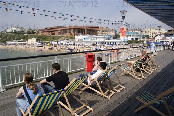 ENGLAND, Dorset, Bournemouth, The West Beach from The Pier with the BICC Bournemouth International Conference Centre and Oceanarium in the distance. Tourists on deckchairs on the pier