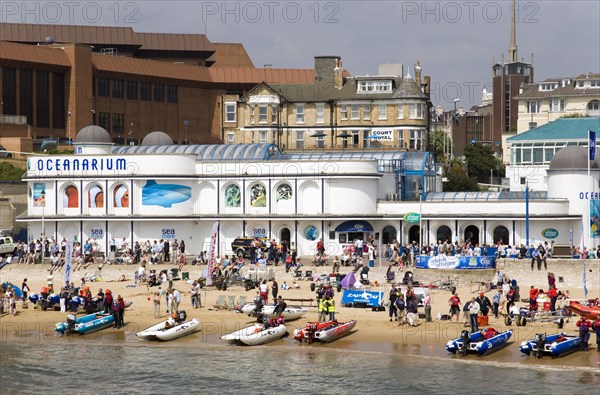 ENGLAND, Dorset, Bournemouth, The West Beach from The Pier with the BICC Bournemouth International Conference Centre and Oceanarium behind. Contestants for Zapcat inflatable speedboat races watch the races from the beach