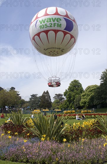 ENGLAND, Dorset, Bournemouth, The Bournemouth Eye balloon lifting off in The Upper Pleasure Gardens with tourists on the grass and the pathways
