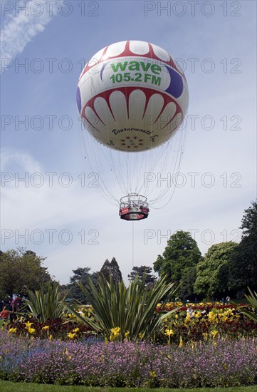 ENGLAND, Dorset, Bournemouth, The Bournemouth Eye balloon lifting off in The Upper Pleasure Gardens with tourists on the grass and the pathways