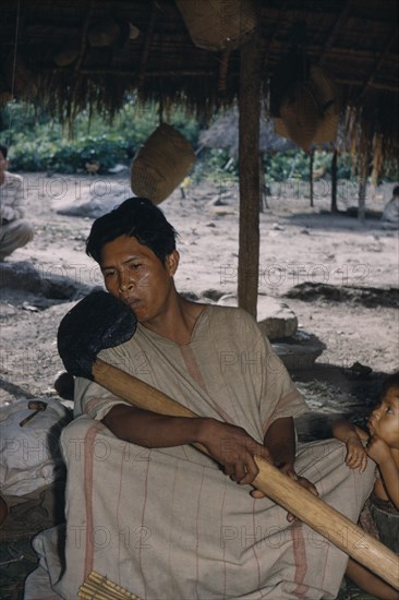 COLOMBIA, Sierra de Perija, Yuko - Motilon ., "Headman playing beeswax axe-head flute, the body made from very light “yarumo” (a type of balsa) wood. Wearing finely woven cotton “manta”  / cloak"