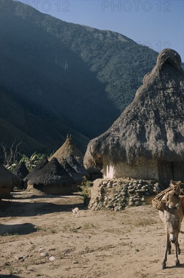 COLOMBIA, Sierra Nevada de Santa Marta, Kogi Tribe, "San Miguel, a Kogi village in foothills of  Sierra Nevada. Sacred pots at apex of conical thatched roofs."