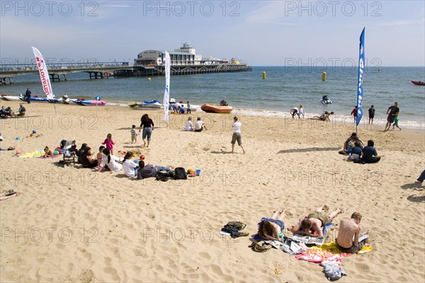 ENGLAND, Dorset, Bournemouth, Tourists on the sand of the West Beach beside the pier.
