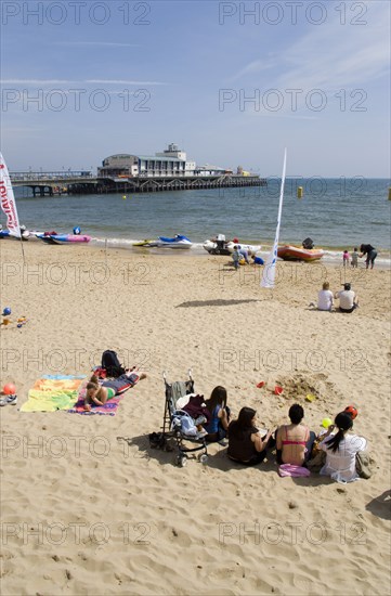 ENGLAND, Dorset, Bournemouth, Tourists on the sand of the West Beach beside the pier.