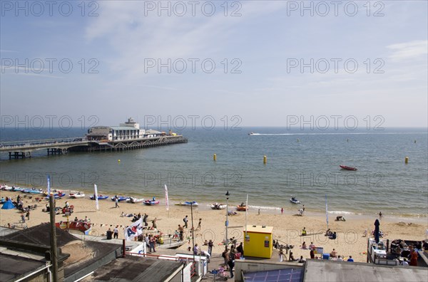 ENGLAND, Dorset, Bournemouth, Tourists on the sand of the West Beach beside the pier.