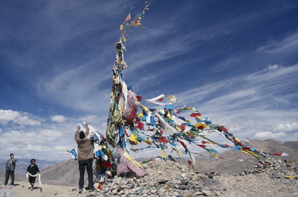 CHINA, Tibet, Tscho La, "Tibetans adding katas, Buddhist ceremonial scarves, to the prayer flags at the top of Tscho La."