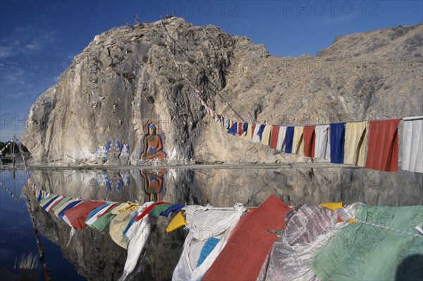 CHINA, Tibet, "Carved Buddha, Buddhist paintings and prayer flags on a rock wall by the road from Lhasa to the airport."