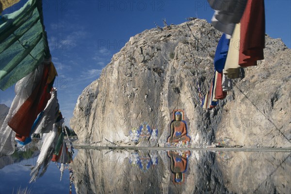 CHINA, Tibet, "Carved Buddha, Buddhist paintings and prayer flags on a rock wall by the road from Lhasa to the airport."