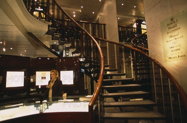 SWITZERLAND, Geneva, Interior of jewellery shop on Rue du Rhone with sales assistant standing behind display counter.