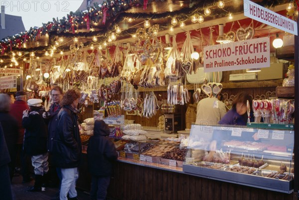 GERMANY, Bayern, Bamberg, "Customers at decorated stall in Christmas market selling iced biscuits, sweets and cakes."