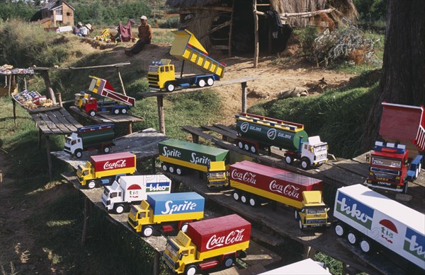 MADAGASCAR, Markets, Road to Antsirabe. Colourful toy vehicles made from locally grown balsa wood painted with famous brand names