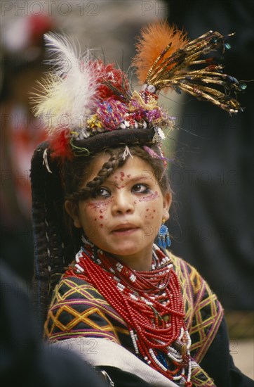 PAKISTAN, North West Frontier Province, Bumburet, "A young Kalash girl in traditional dress at the Chilimjusht Festival. Decorated face, lots of beaded necklaces and earrings."
