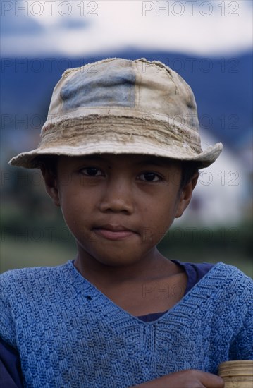 MADAGASCAR, People, children, Road to Ambositra. Portrait of a young boy wearing a dirty hat and blue knitted sweater