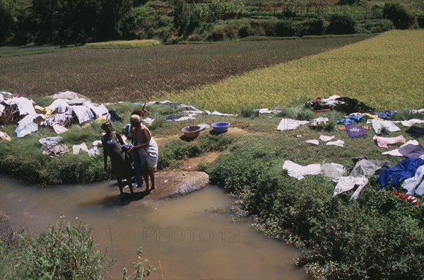 MADAGASCAR, Work, Near Ambositra. Women doing laundry in a river with the clothes left to dry in the sun along the river banks