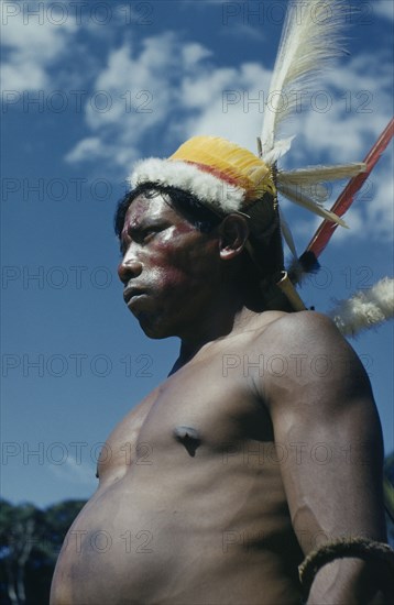 COLOMBIA, Vaupes Region, Tukano Tribe, "Man with ceremonial feather head-dress – crown of white egret down, macaw and toucan breast feathers, royal crane and macaw tail feathers; forest nut arm band, red “Achiote” berry facial paint"