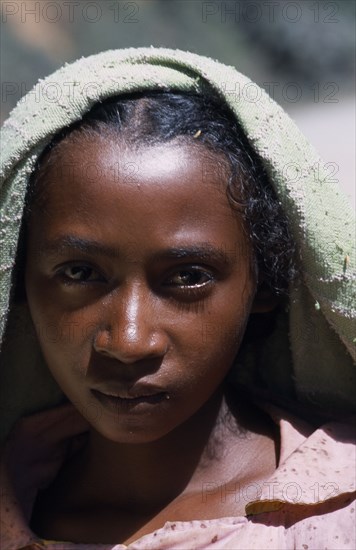 MADAGASCAR, People, Children, Road to Ranomanfana. Head and shoulders portrait of a girl wearing a pink shirt with a green scarf draped across her head