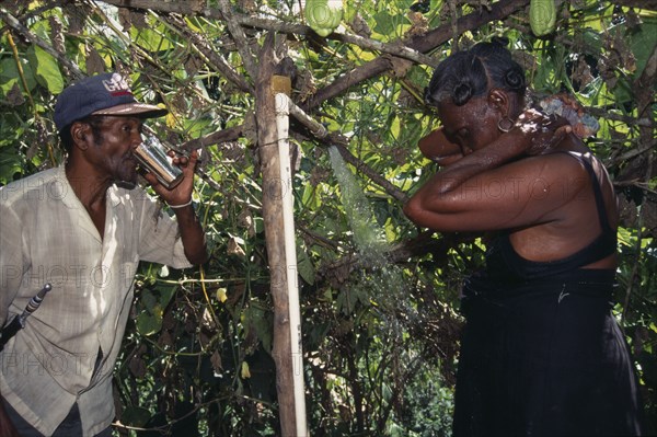 DOMINICAN REPUBLIC, Water, Man drinking water and a woman washing under a shower from a aqueduct outside their home