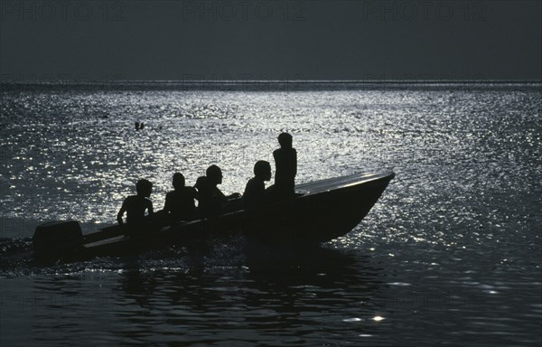 JAMAICA, Transport, People traveling on a motorboat at night silhouetted against the light of the moon
