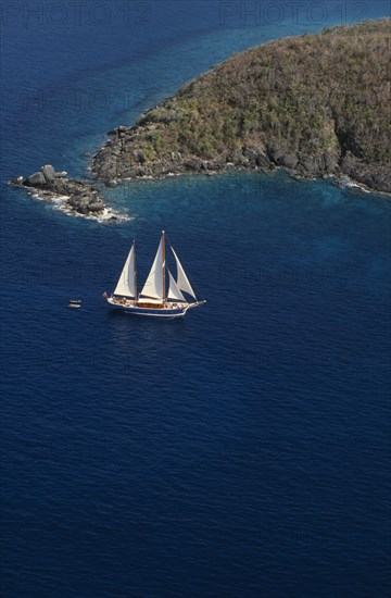 WEST INDIES, US Virgin Islands, St Thomas, Elevated view over sailing boat passing rocky projectory.