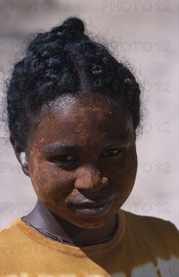 MADAGASCAR, Tulear, Ifaty Beach. Head and shoulders portrait of a young girl wearing mud mask on her face to protect her skin from the sun