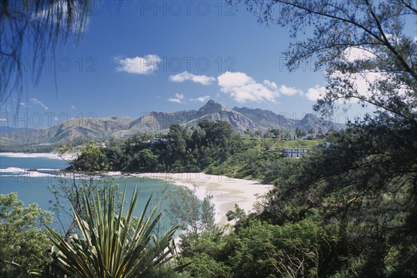 MADAGASCAR, Fort Dauphin, Libanona Beach with view across plants and vegetation towards sandy stretch of beach and sea with mountains in the distance
