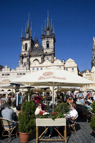 CZECH REPUBLIC, Bohemia, Prague, People sitting at restaurant tables under umbrellas in the Old Town Square in front of the Church of Our Lady before Tyn