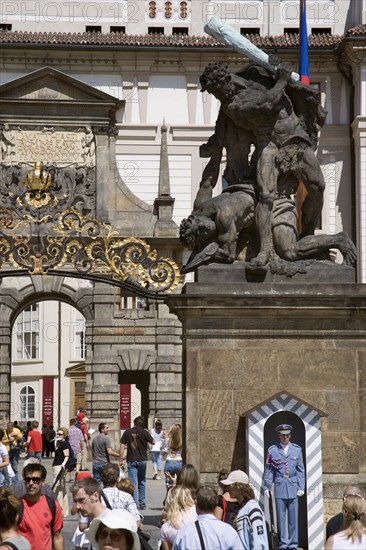 CZECH REPUBLIC, Bohemia, Prague, Tourists at the entrance to Prague Castle in Hradcany with a sentry standing guard beneath an 18th Century statue of fighting giants by Ignaz Platzer