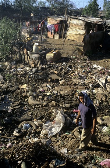 NICARAGUA, Managua Province, Managua, "The 'waste basket of Chureca' has existed since the late 1960's in the Acahualinca district of Managua, Nicaragua. It covers 42 hectares, is bombarded with thousands of tonnes of waste a day and is home to over 170 struggling families. By day over 1500 more Nicaraguans arrive at the site, some of whom are children who have been sent by their parents, others come by their own initiative. All compete with the adults to find, harvest and re-sell recyclable material. Of the minors who go to the waste basket - 88% it has respiratory problems, 62% suffer from parasites and 42% have serious skin diseases. Although the sky is clear and blue the air is thick of burning waste or rotting waste. Little houses or 'casitas' lie in a mixed muddle of rubbish and waste. The house at the back of shot is made up of an eclectic collection of doors, wooden planks, dustbin bags, hanging bits of ripped tarpaulin, corrugated iron strips and whatever waste material seems ...